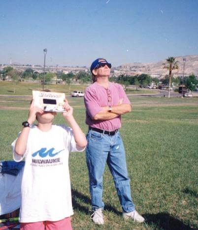 Mark, founder of Rainbow Symphony, looking at an eclipse with his son